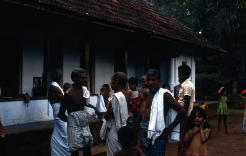 Village men and children are in front of the house