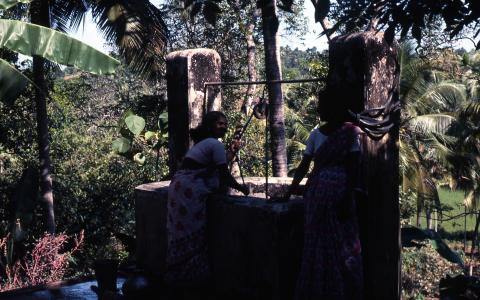 கிணற்றில் இருந்து இரண்டு பெண்கள் தண்ணீரை இழுக்கும் புகைப்படம்
