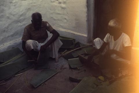 Two elderly people prepare banana leaves for Annathanam
