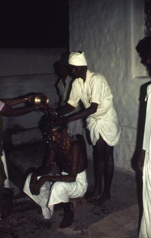 Pouring water on the head of a man