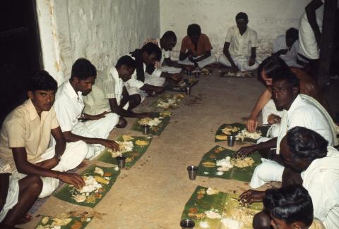 A group of men eats on banana leaves